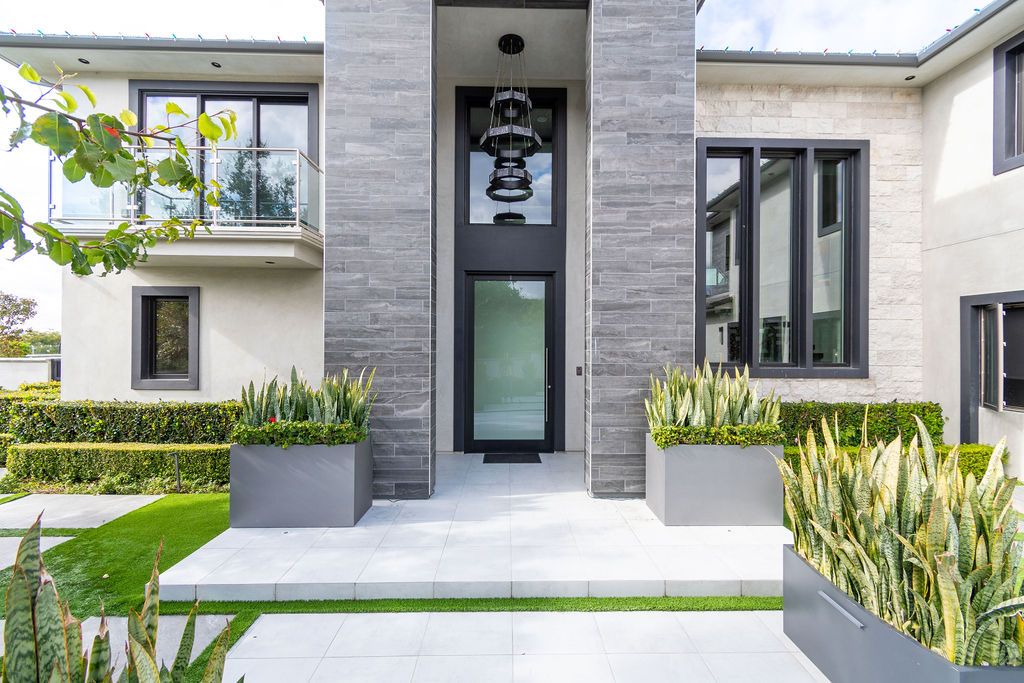 The front of a large house with lots of windows and planters in front of it.