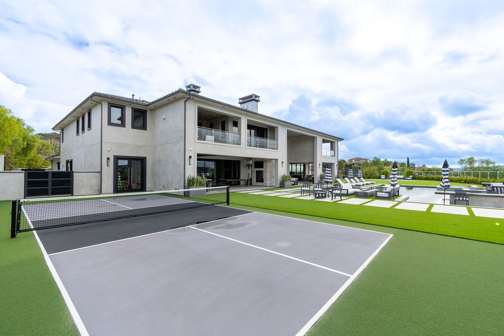 A large house with a tennis court in front of it.