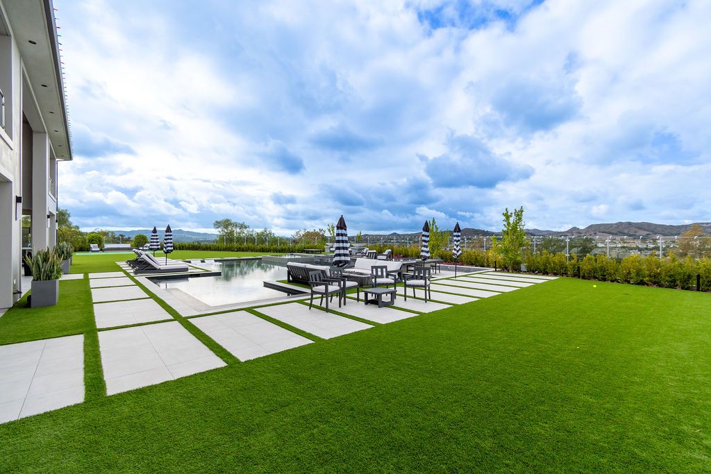 A large lawn with a swimming pool in the backyard of a house.