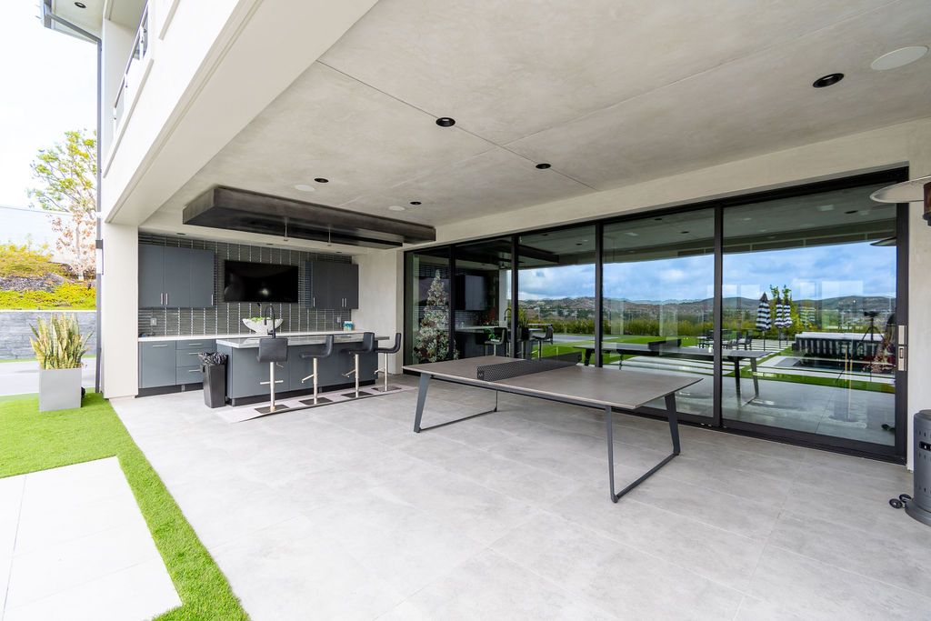 There is a ping pong table on the patio of a house.