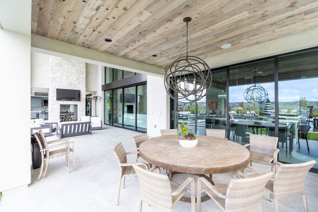 A large patio with a table and chairs and a chandelier hanging from the ceiling.