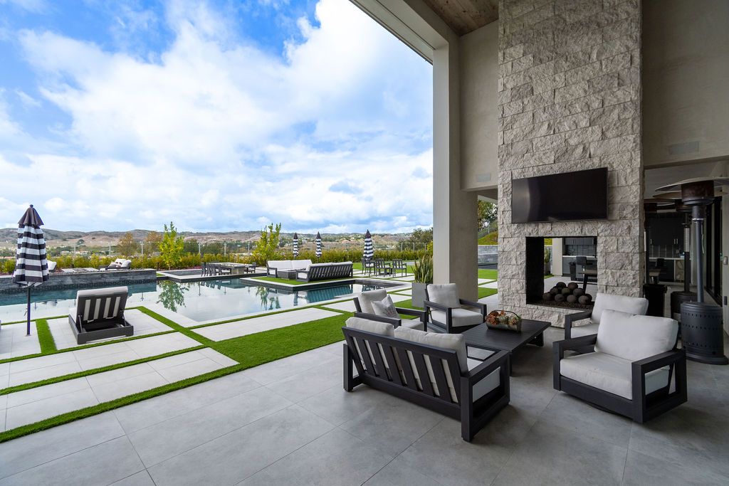 A patio with a fireplace , couch , chairs , table and television.