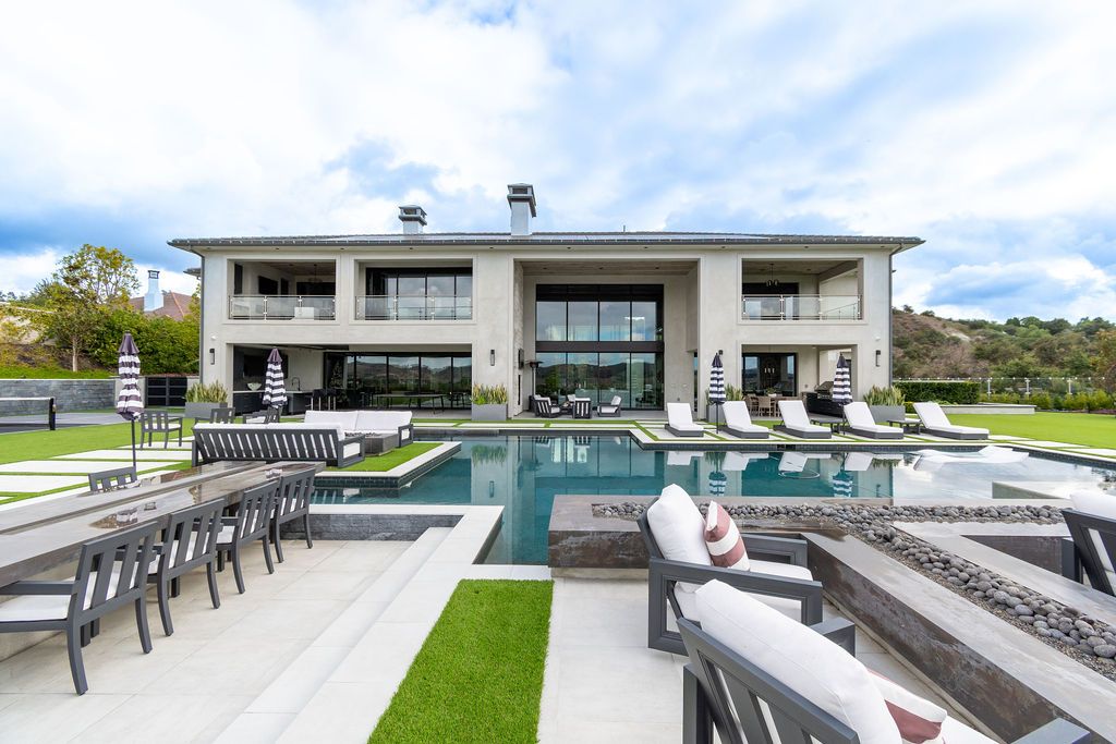 A large house with a swimming pool and patio furniture in front of it.