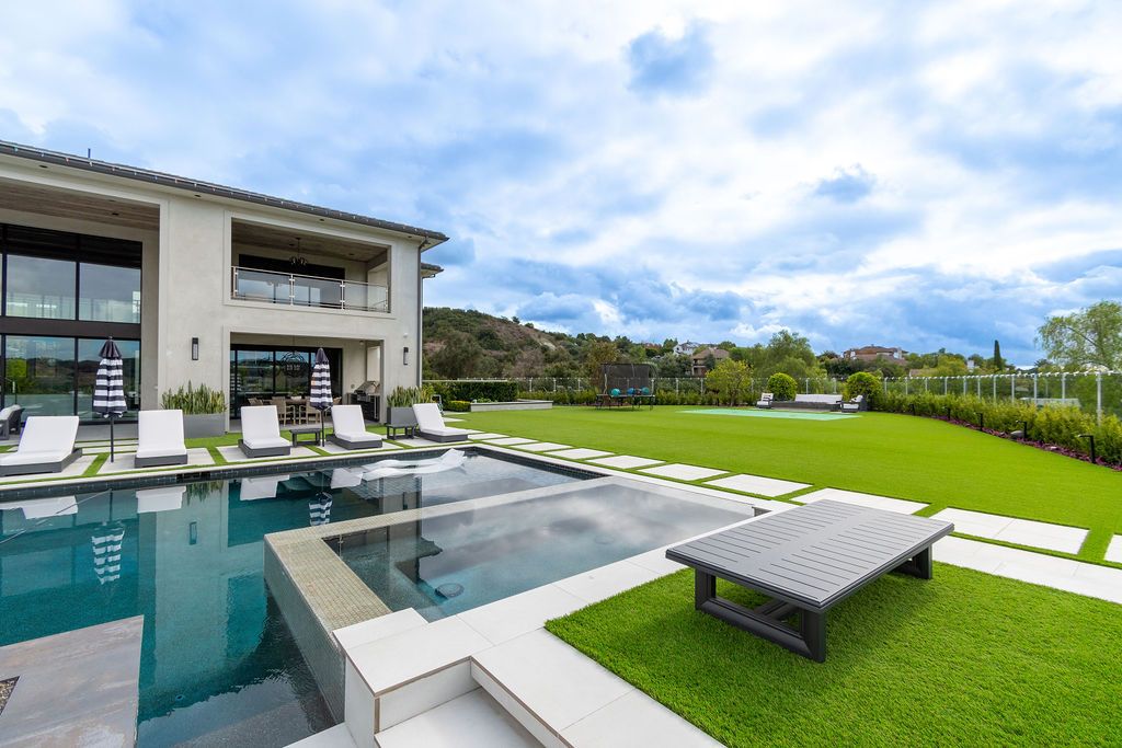 A large house with a swimming pool and lawn chairs in front of it.