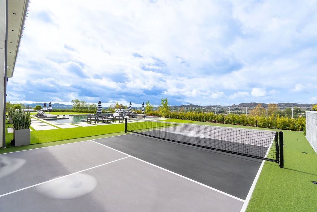A tennis court with a net and a pool in the background.