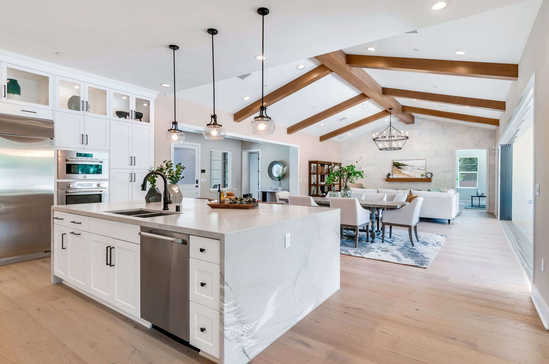 A kitchen with white cabinets and stainless steel appliances and a large island in the middle.