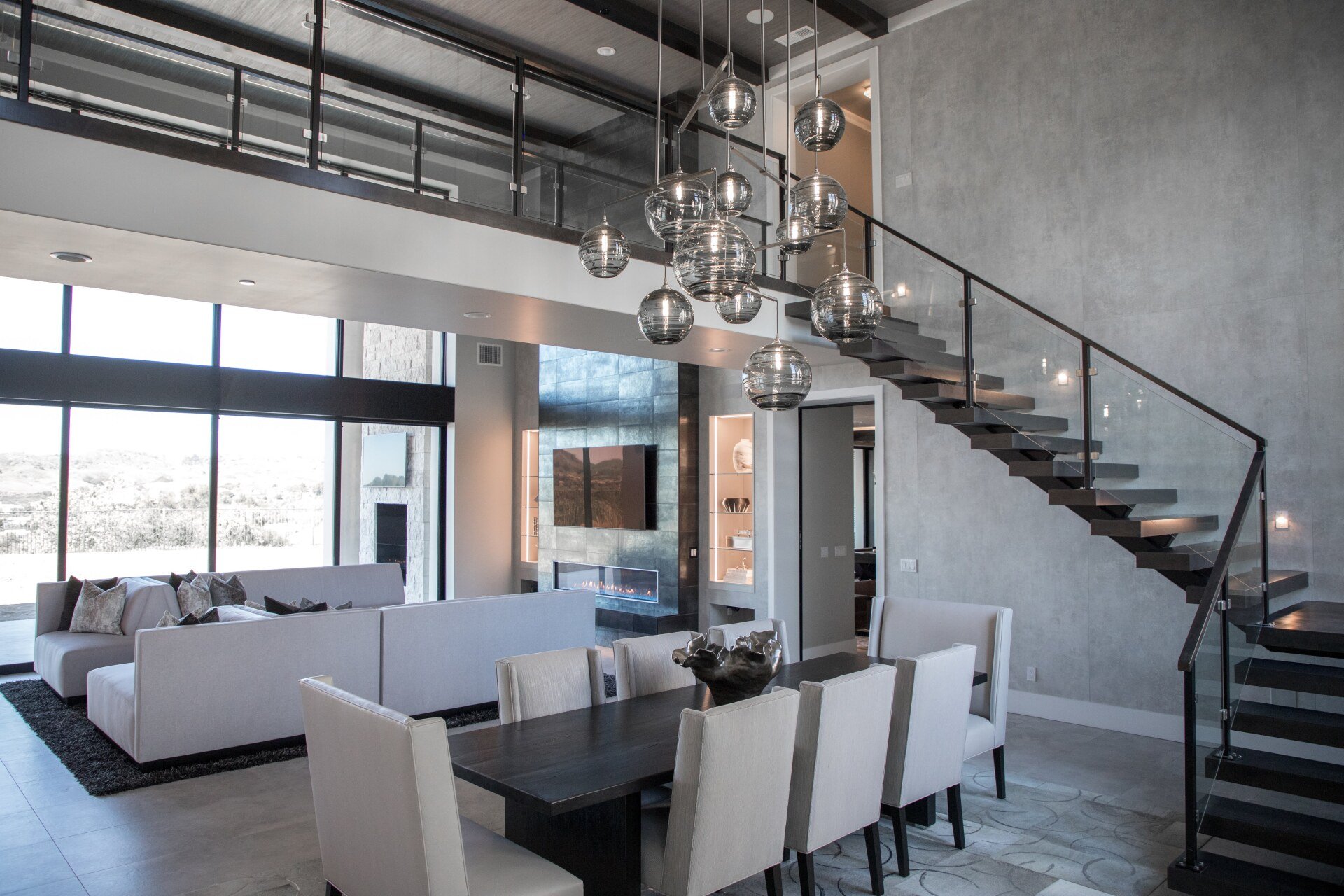 A living room with a dining table and chairs and a staircase leading to the second floor.