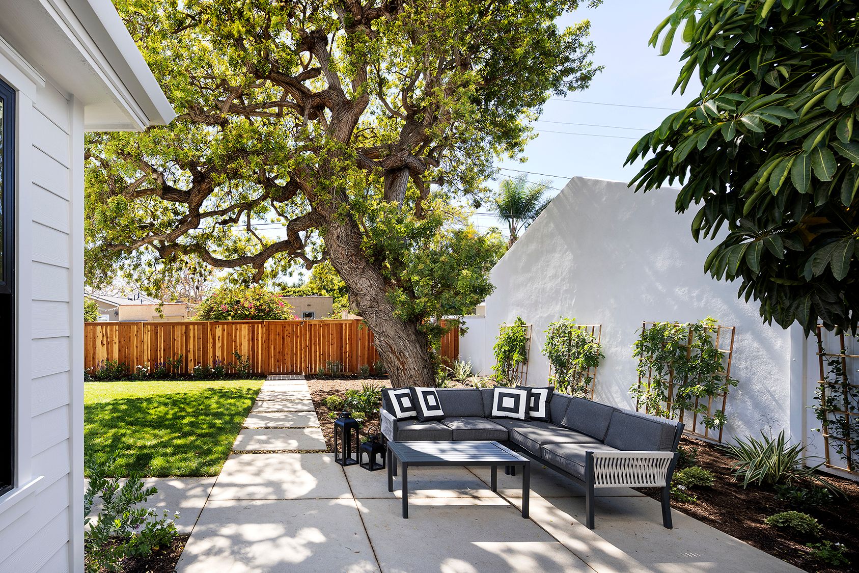 A patio with a couch and a table under a tree