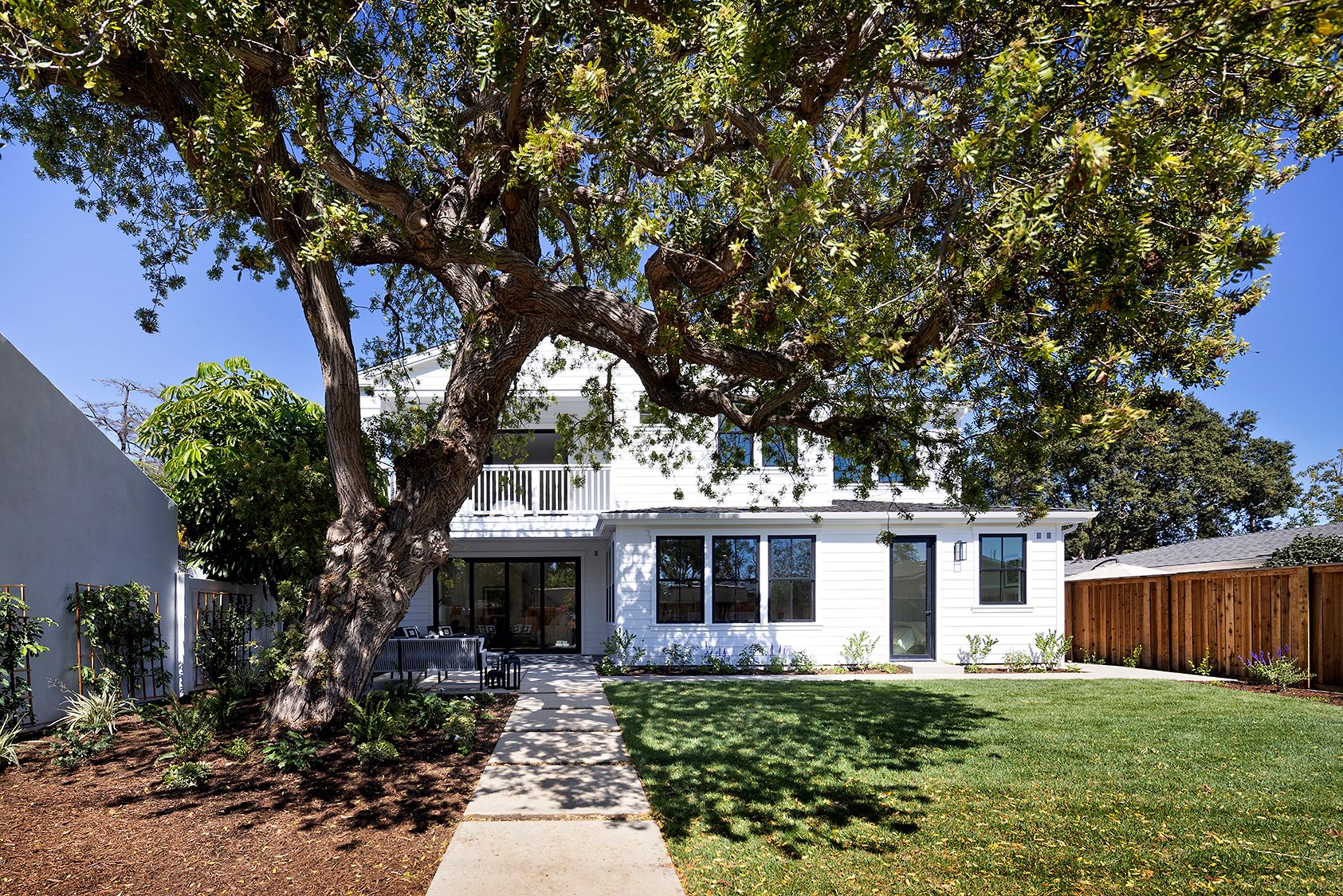 A white house with a large tree in front of it