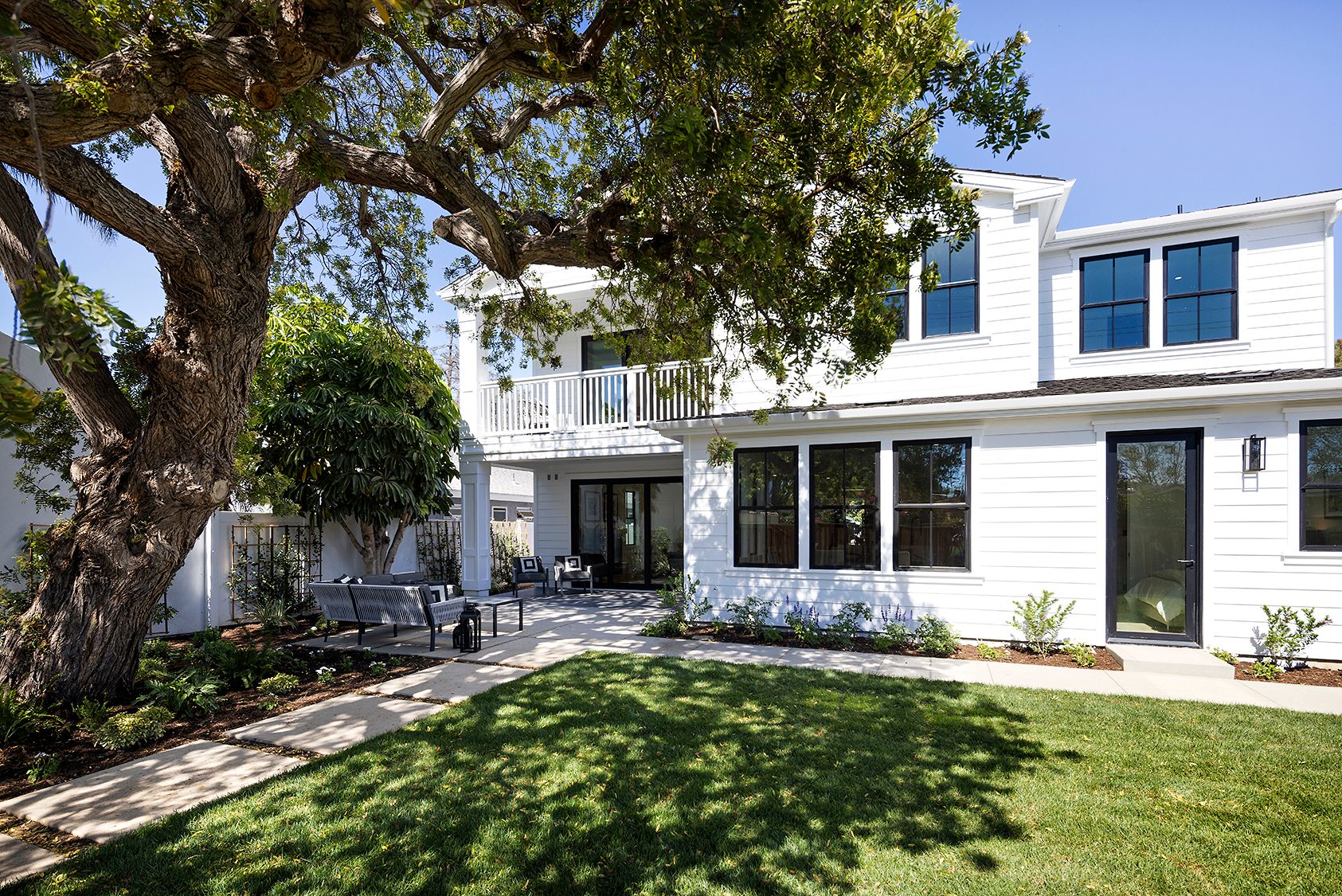 A large white house with a large tree in the backyard.