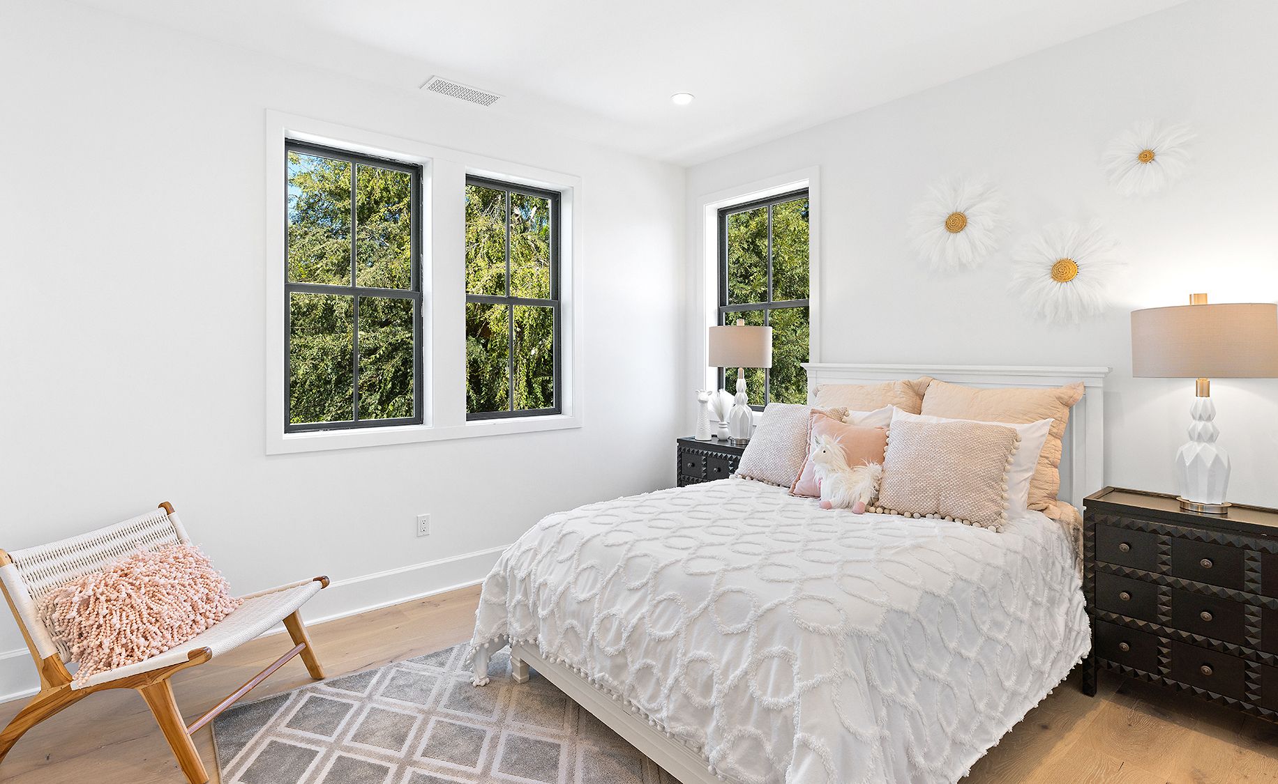 A bedroom with a bed , dresser , chair and two windows.