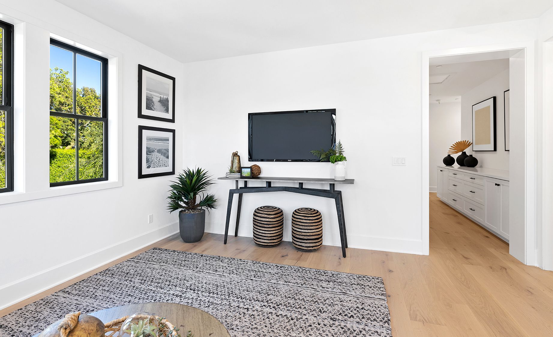 A living room with a television on the wall and a rug.