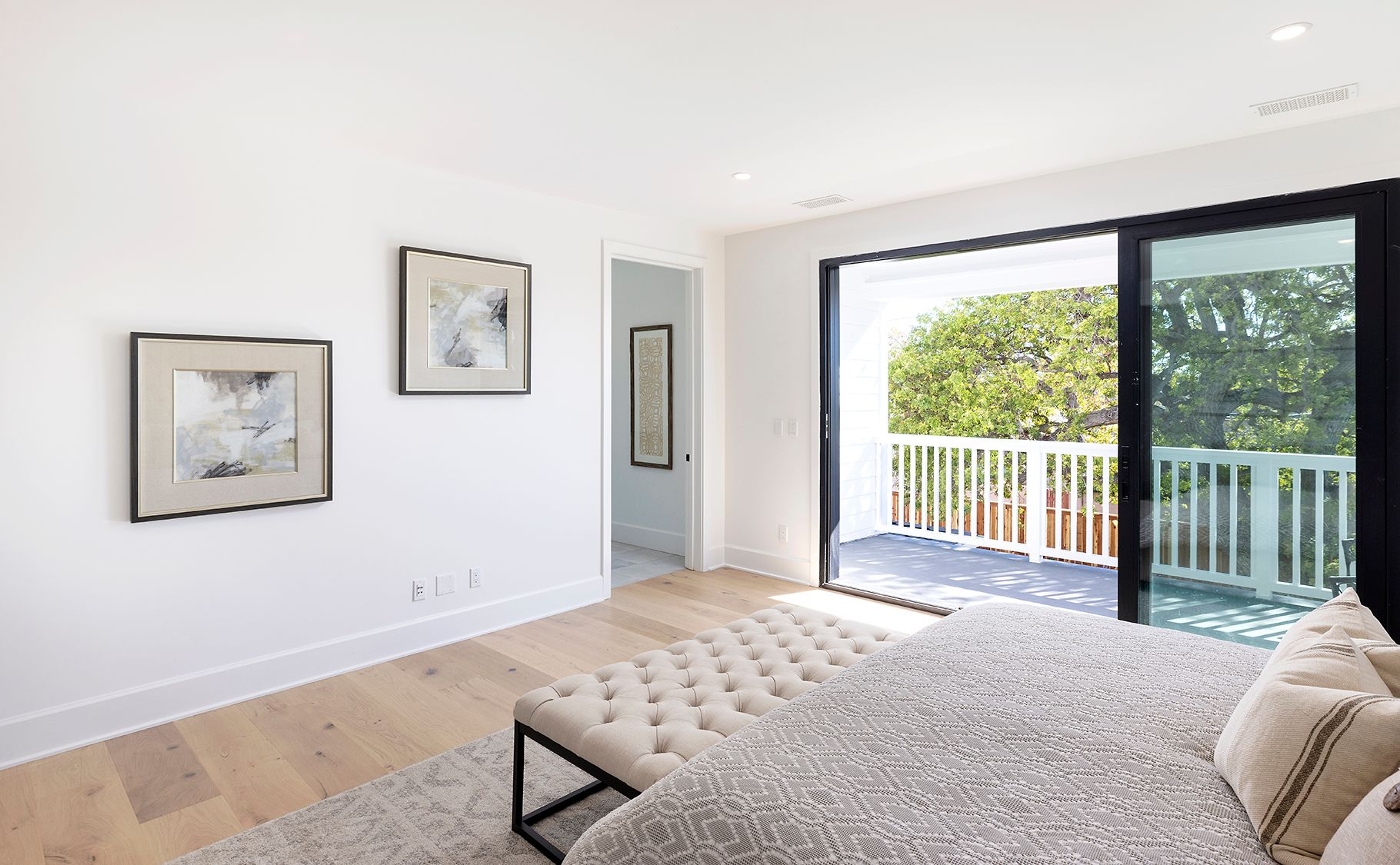 A bedroom with a large bed and a sliding glass door leading to a balcony.