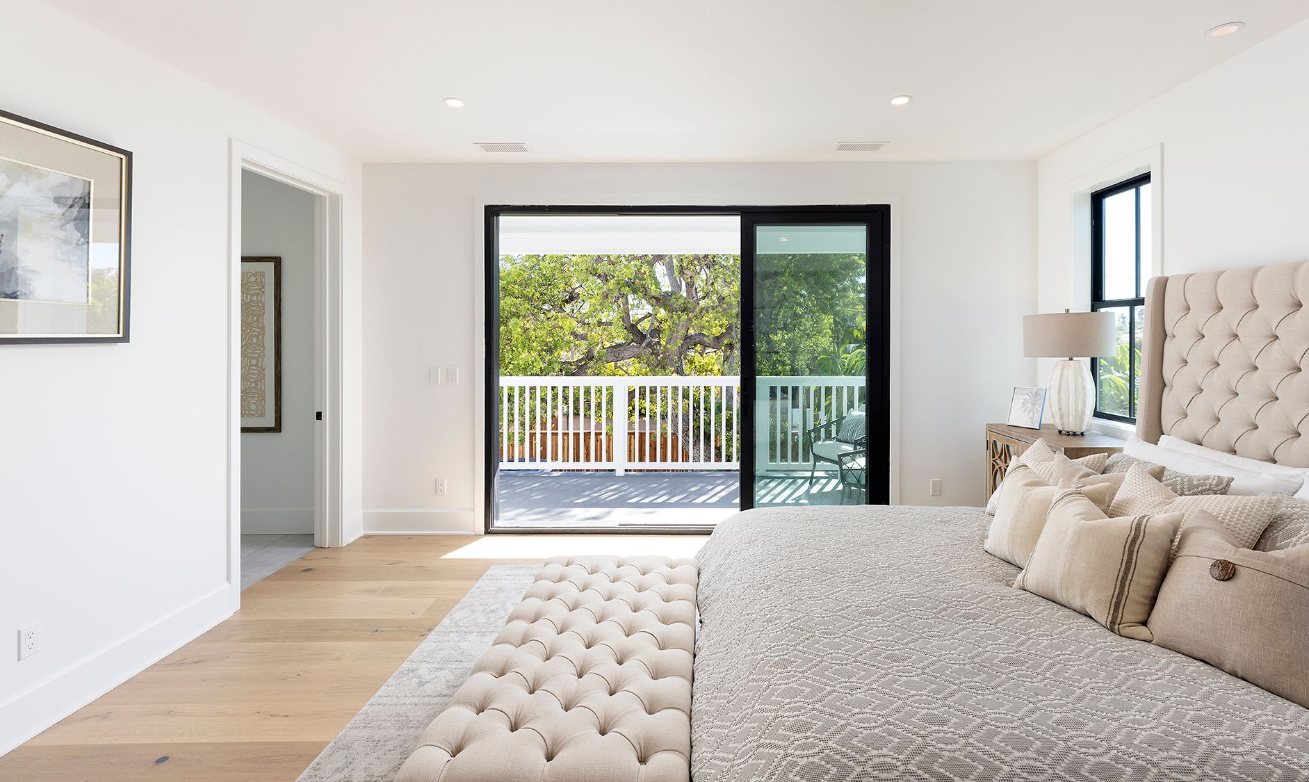 A bedroom with a large bed and a sliding glass door leading to a balcony.