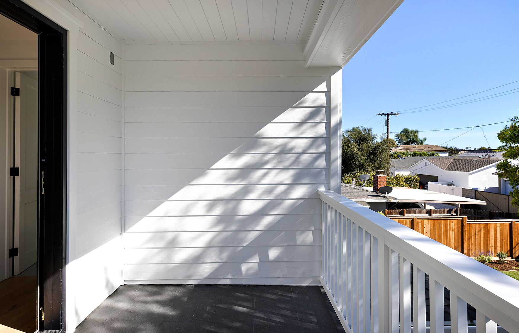 An empty balcony with a white railing and a wooden fence