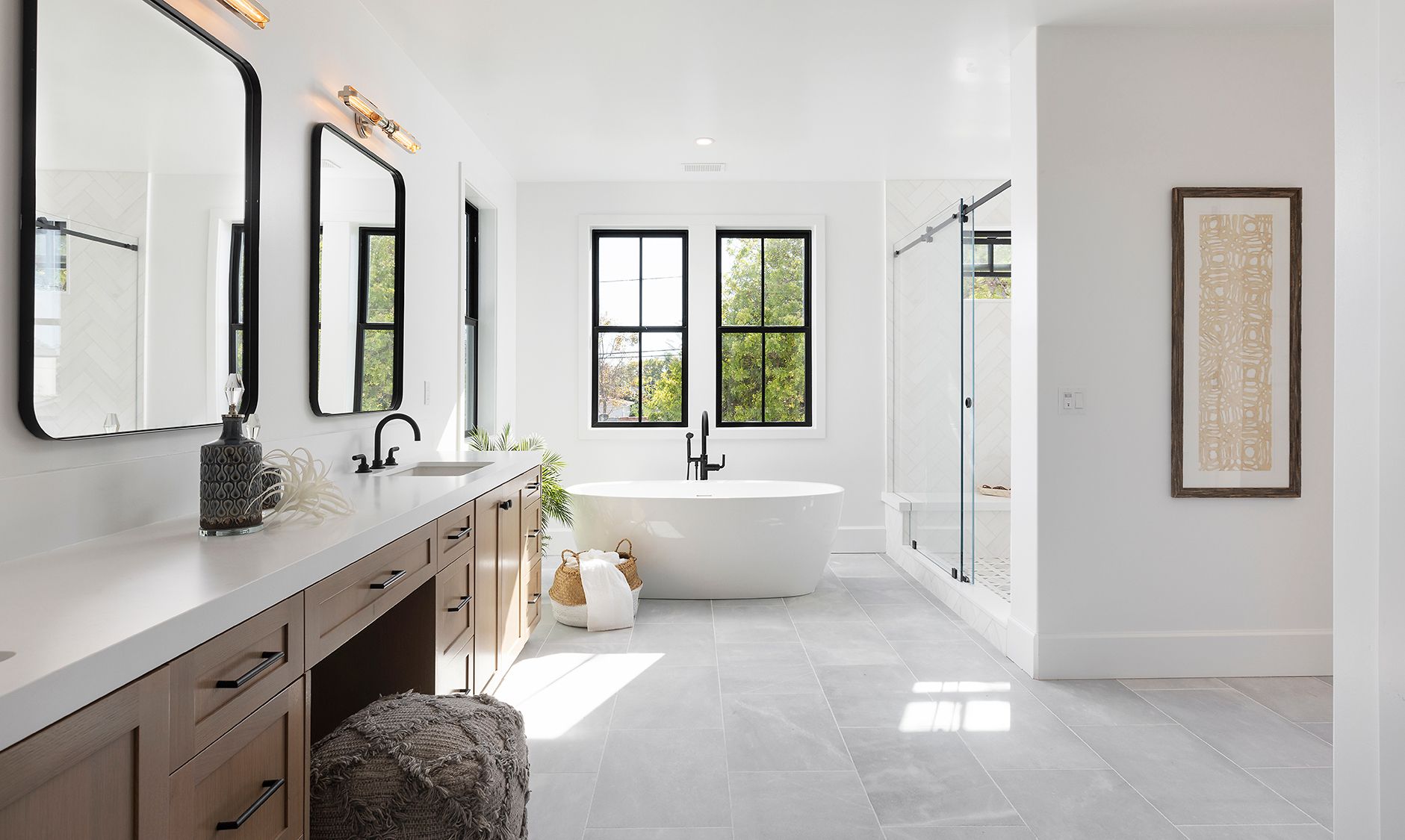 A bathroom with a tub , sink , mirrors and a walk in shower.
