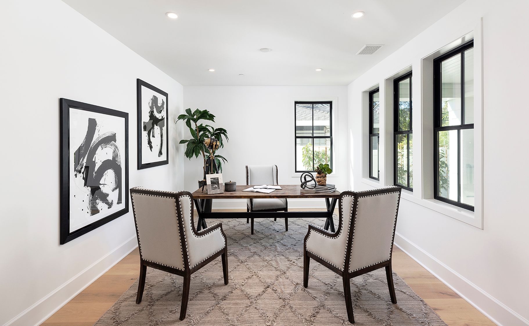 A living room with a desk and chairs and a rug.