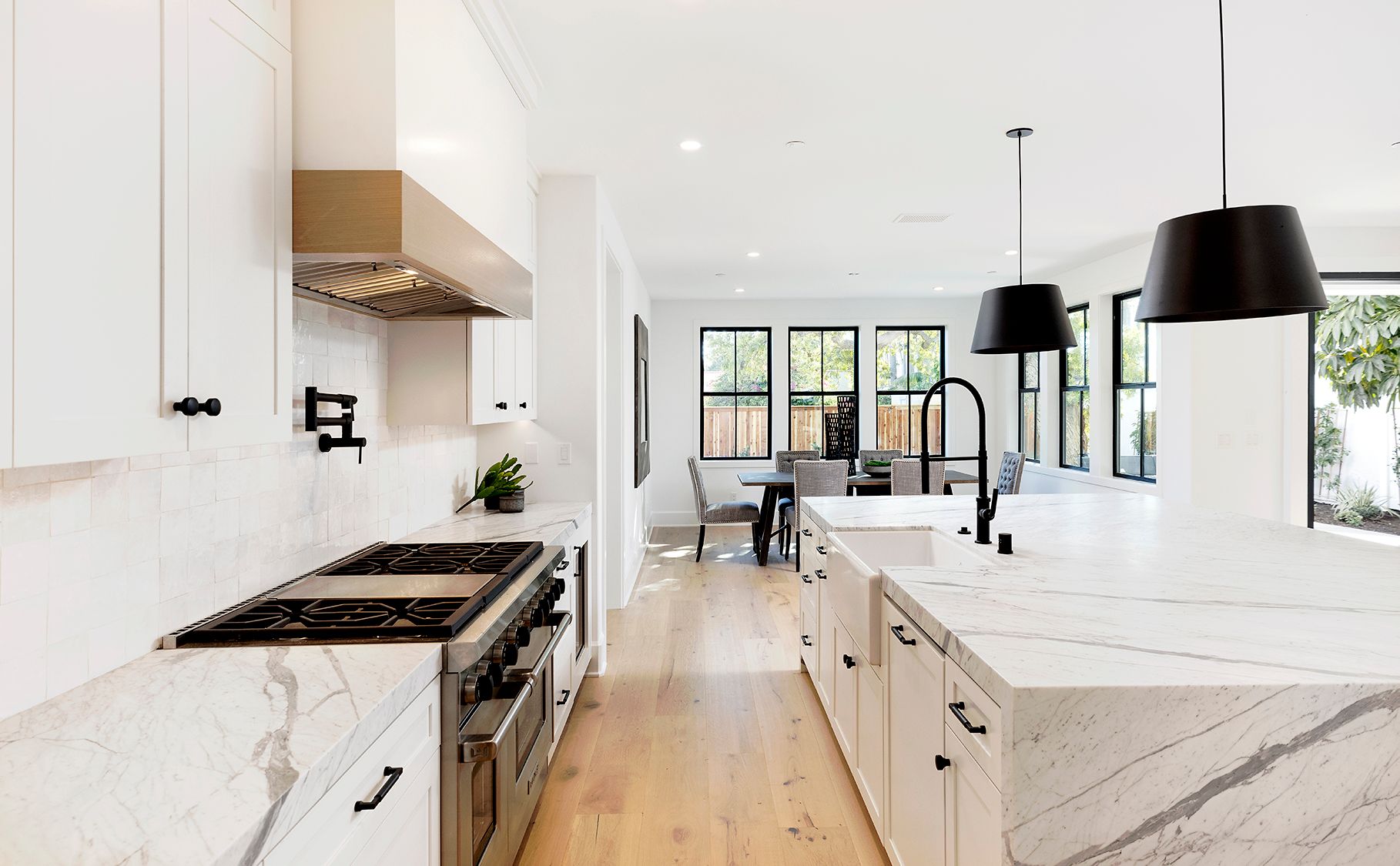 A kitchen with white cabinets , marble counter tops , stainless steel appliances and a large island.