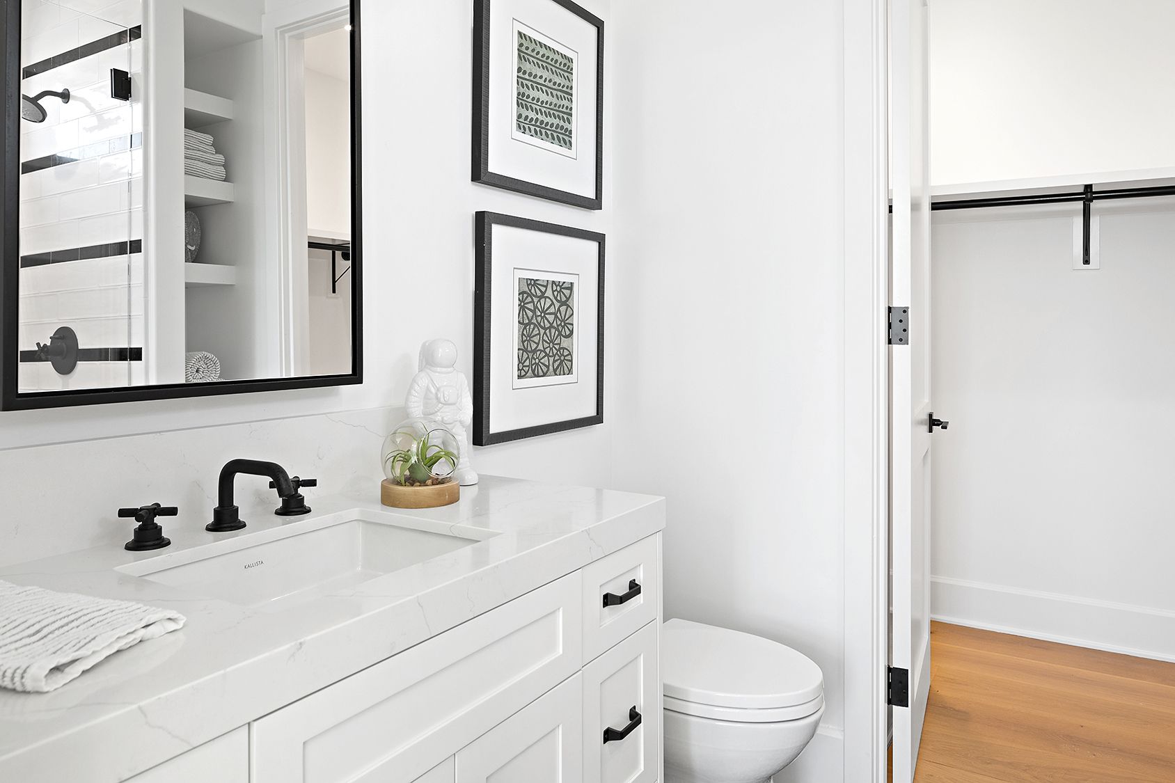 A bathroom with a sink , toilet , mirror and walk in closet.