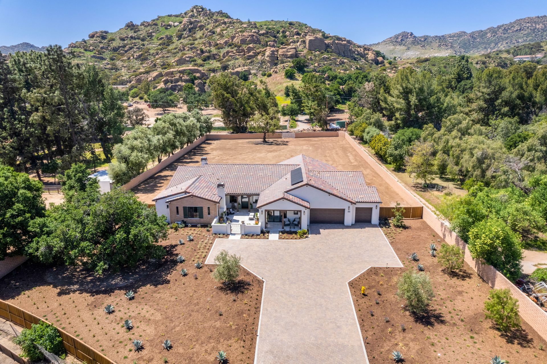An aerial view of a large house surrounded by trees and mountains.