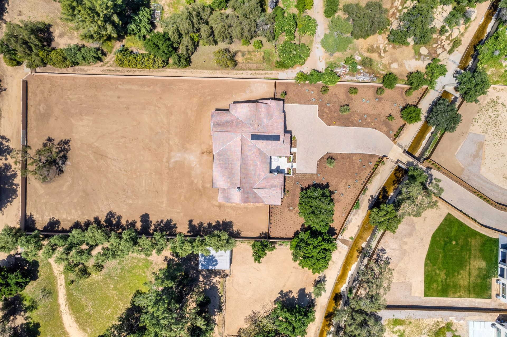 An aerial view of a house surrounded by trees and dirt.
