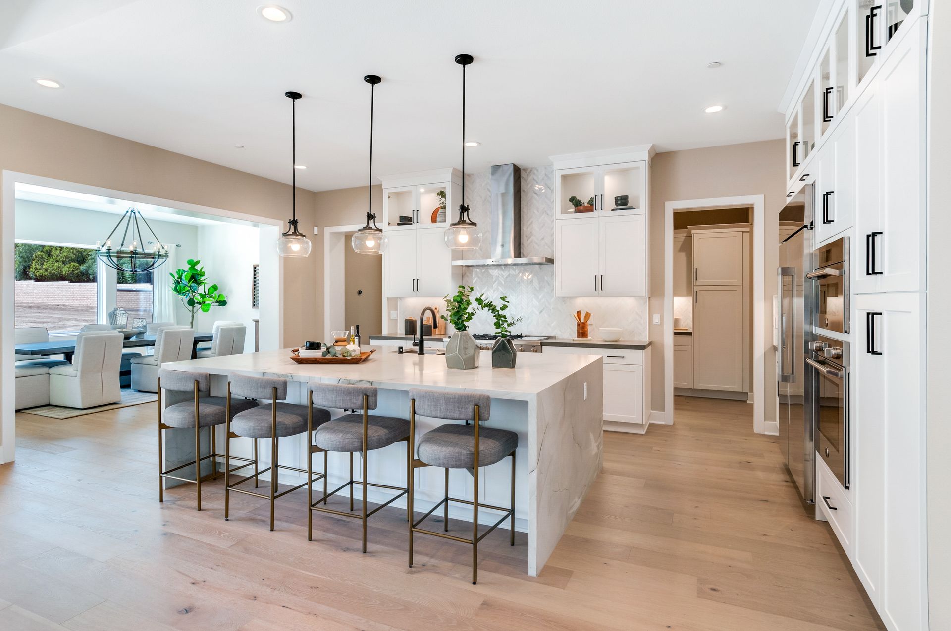 A kitchen with white cabinets , stainless steel appliances , a large island and stools.