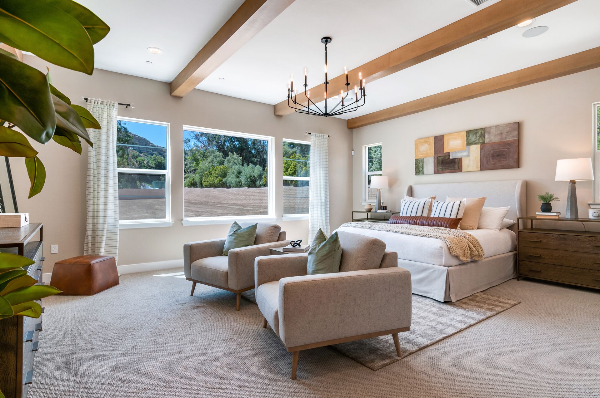 A large bedroom with a king size bed , two chairs , and a chandelier.