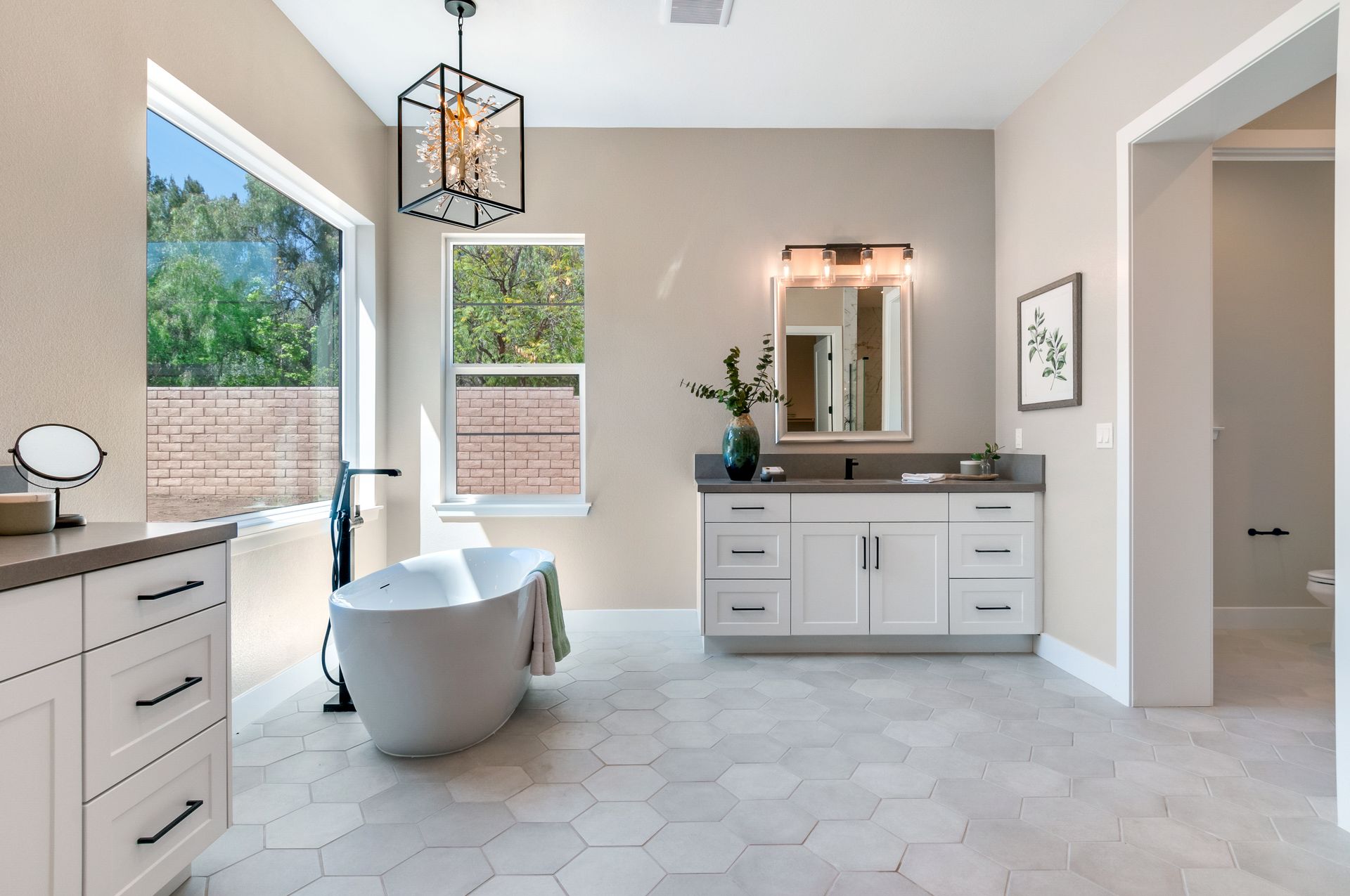 A bathroom with a tub , sink , mirror and window.