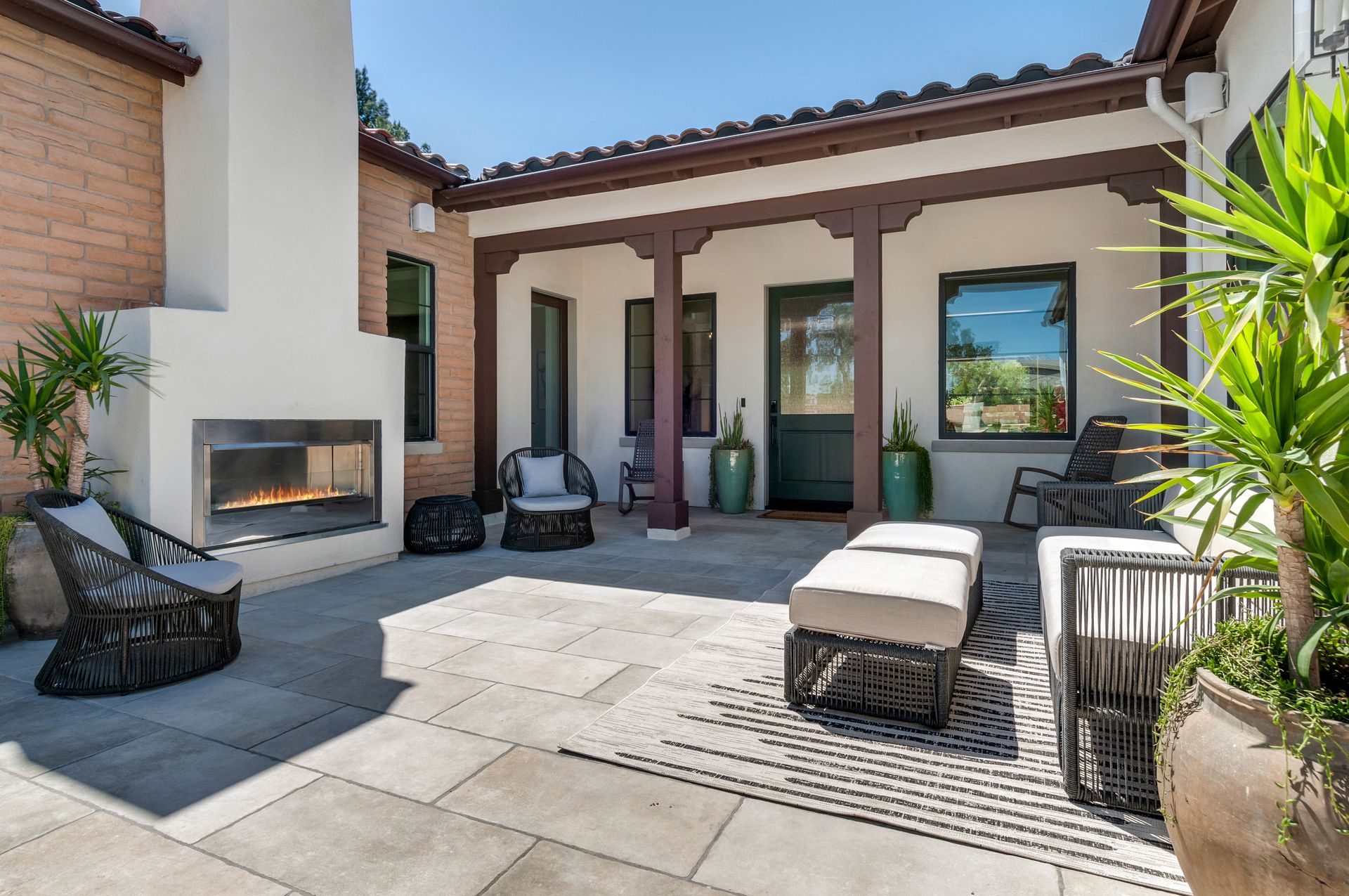 A patio with a fireplace and chairs in front of a house.