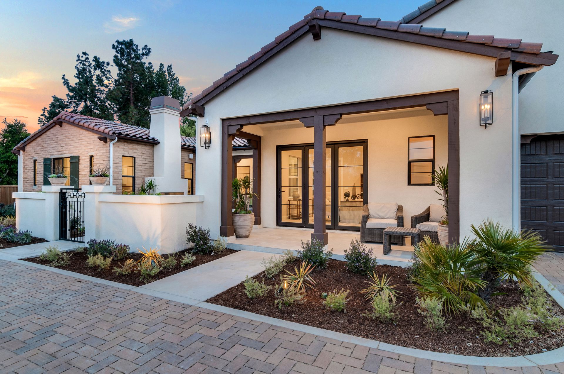 A white house with a porch and a brick driveway