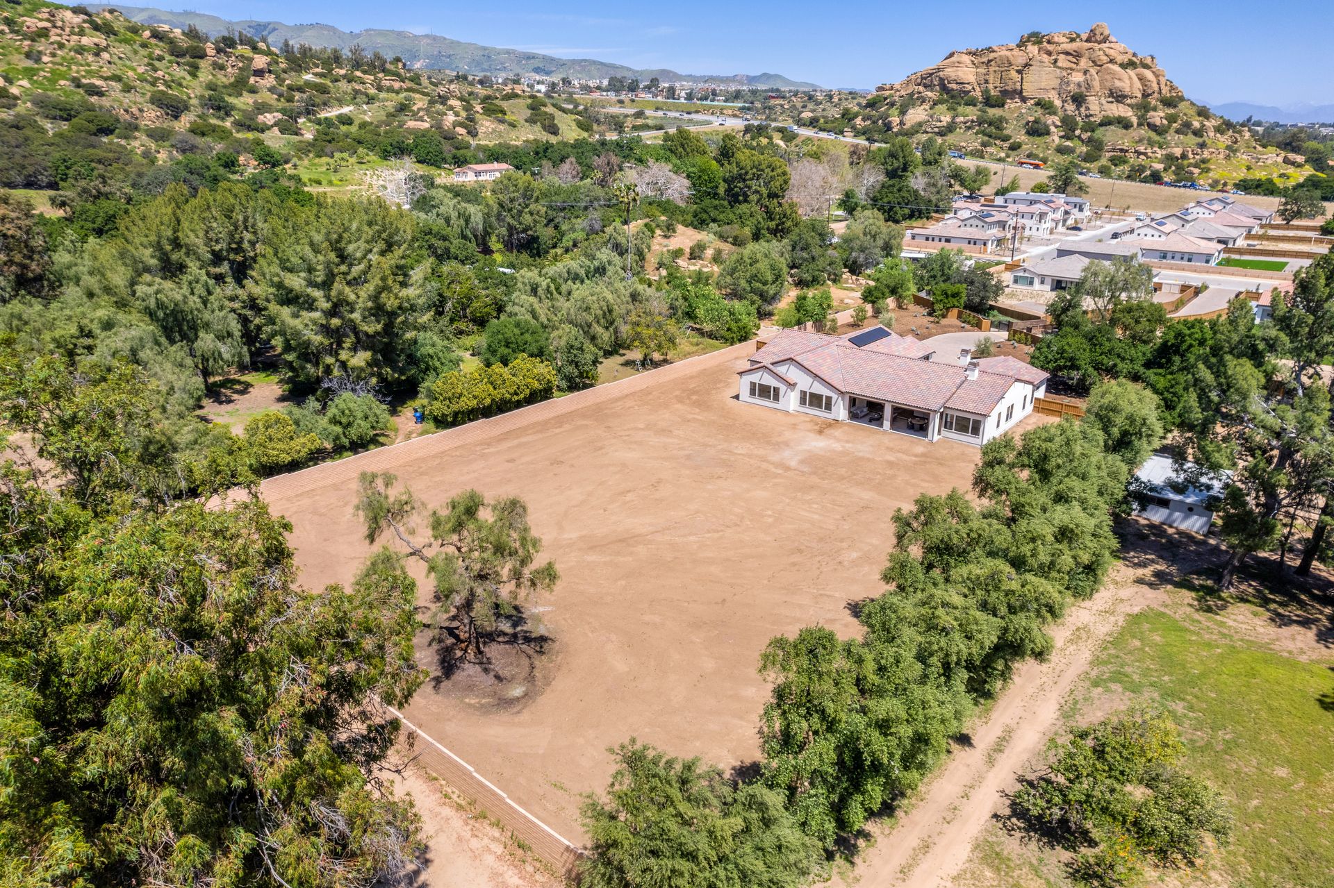 An aerial view of a house in the middle of a field surrounded by trees.