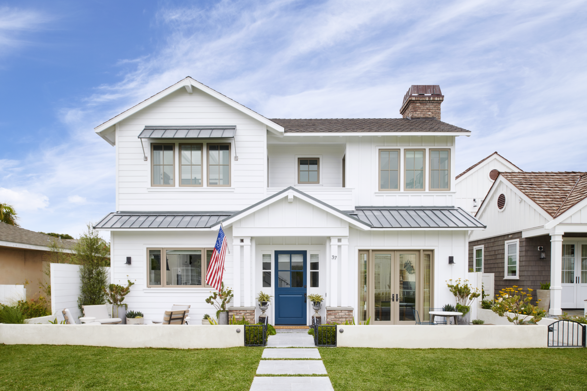 A white house with a blue door and an american flag in front of it.