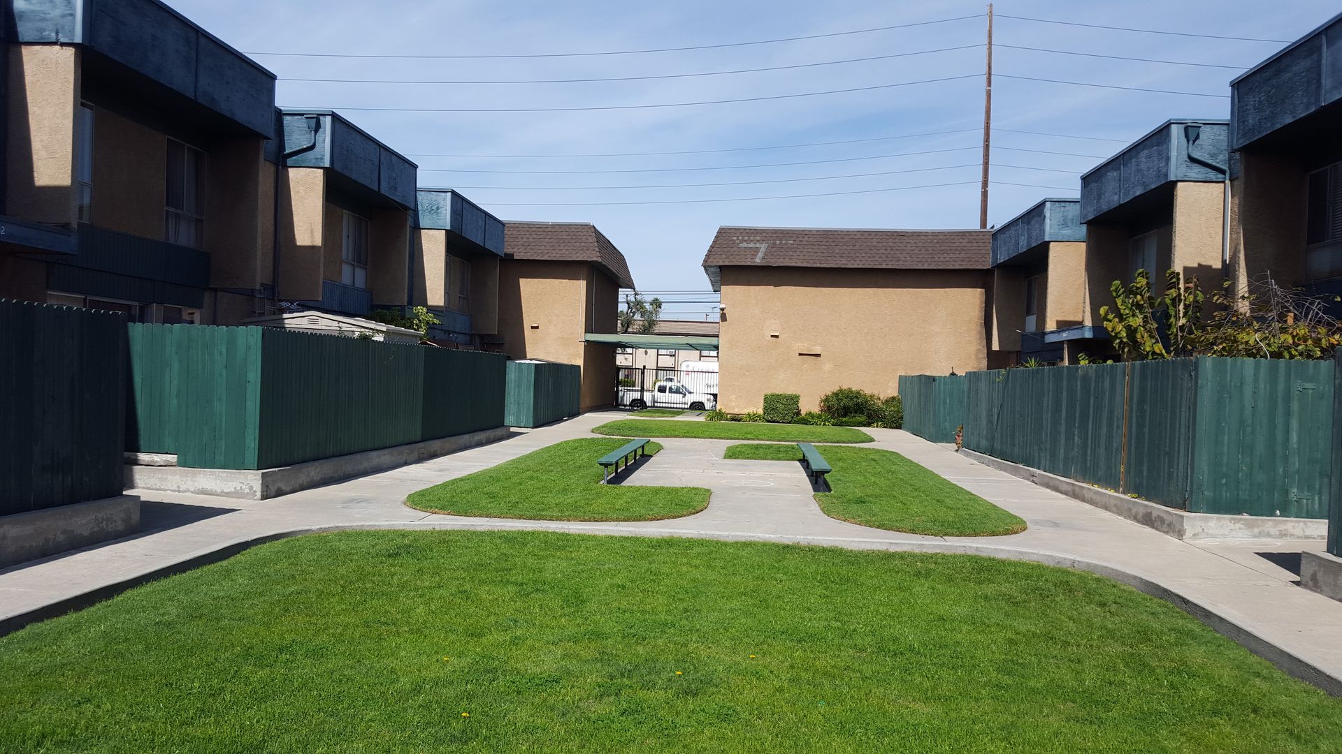 A row of apartment buildings with a lush green lawn in front of them.