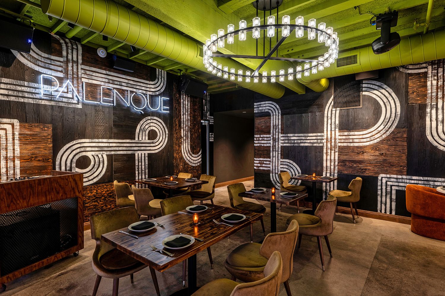 A restaurant with tables and chairs and a neon sign on the wall.