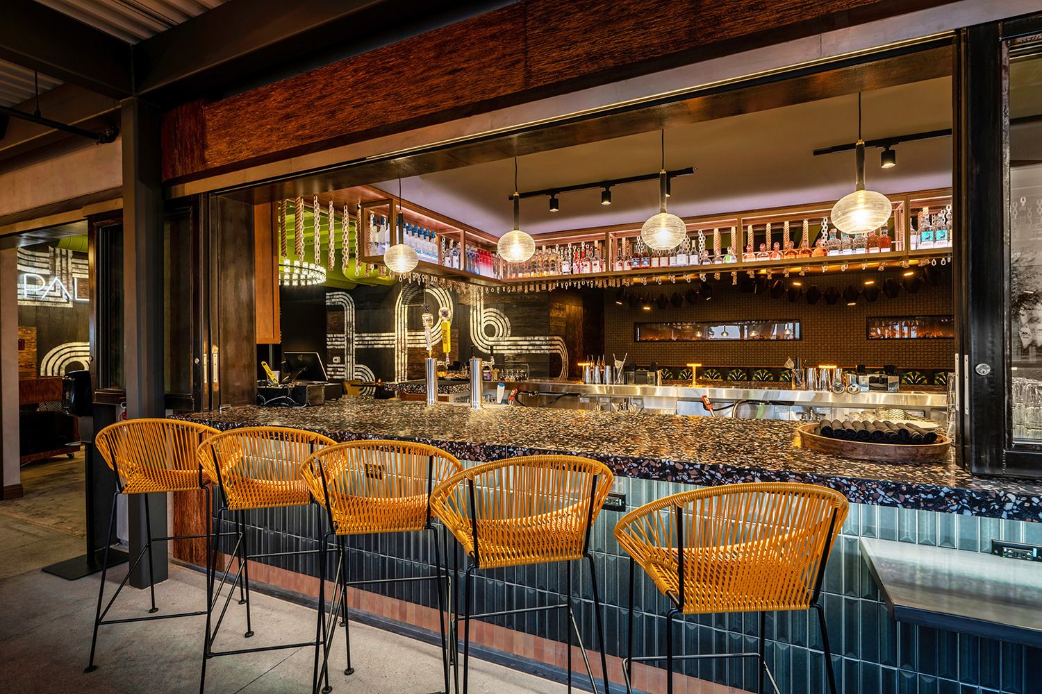 A bar with wicker chairs and a marble counter top.