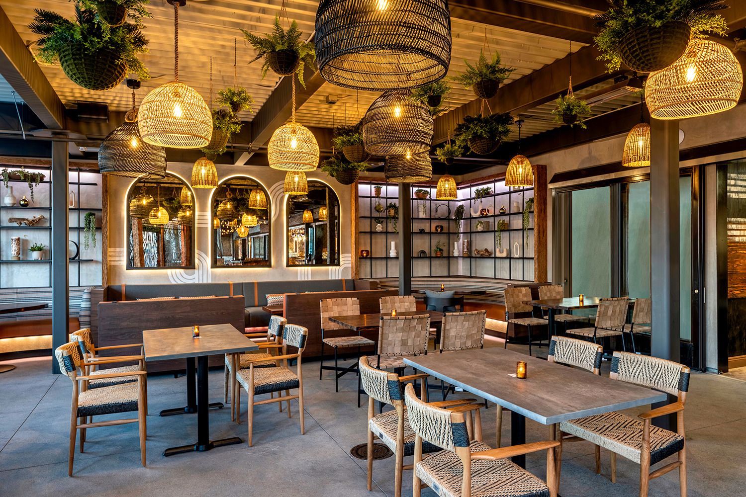 A restaurant with tables and chairs and lots of lights hanging from the ceiling.