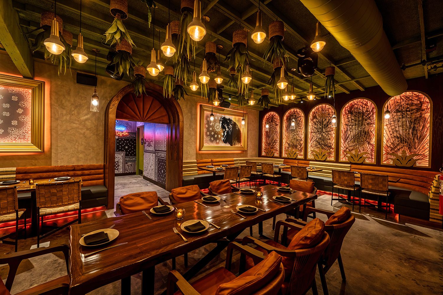 A restaurant with a long table and chairs and a lot of lights hanging from the ceiling.