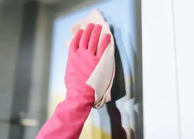 Gloved hand wiping a window with a cloth, cleaning the glass surface