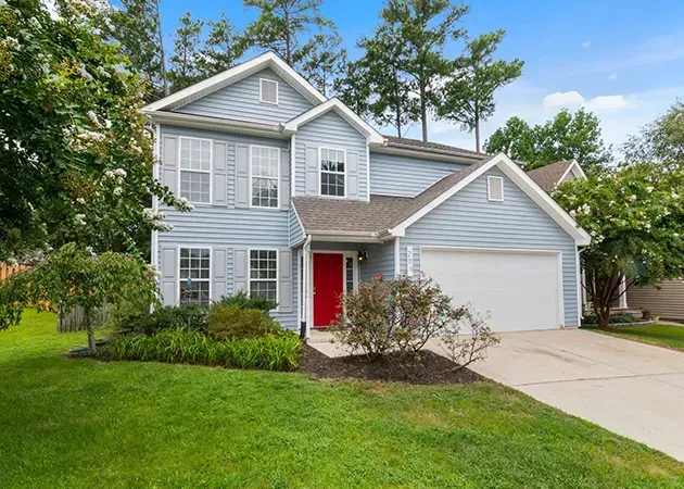 Gray two-story suburban house with red front door, white trim, and a two-car garage