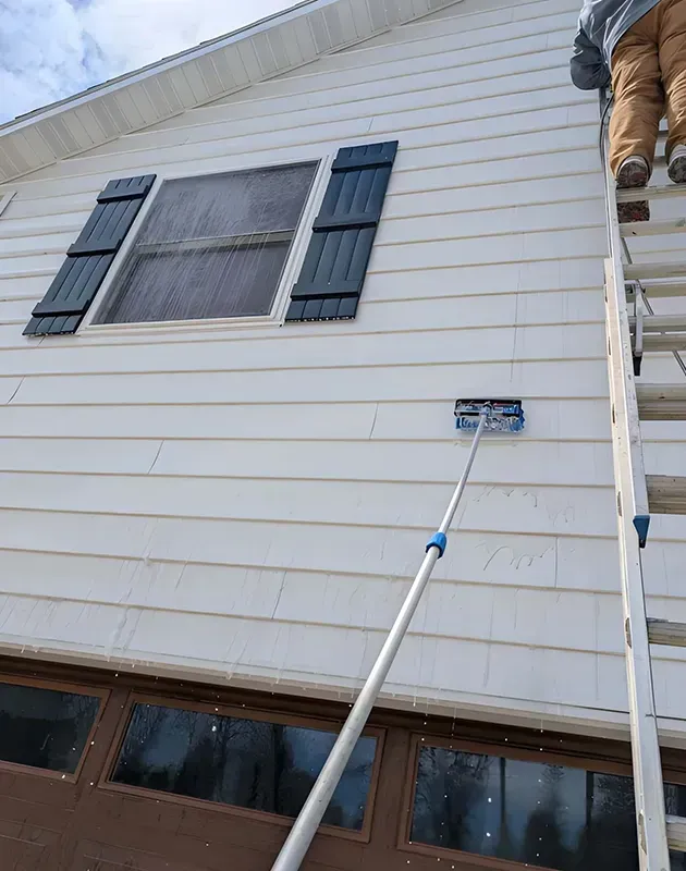 House siding with a window and an extension pole reaching a small blue wall-mounted device