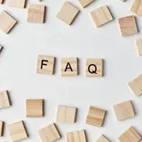 Wooden letter tiles spelling “FAQ” on a white background, surrounded by scattered blank tiles.
