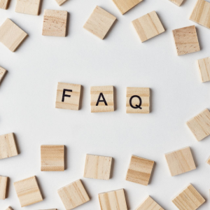 Wooden letter tiles spelling “FAQ” on a white background, surrounded by scattered blank tiles.