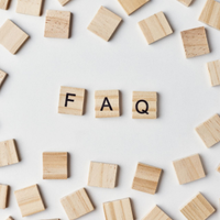 Wooden letter tiles spelling “FAQ” on a white background, surrounded by scattered blank tiles.