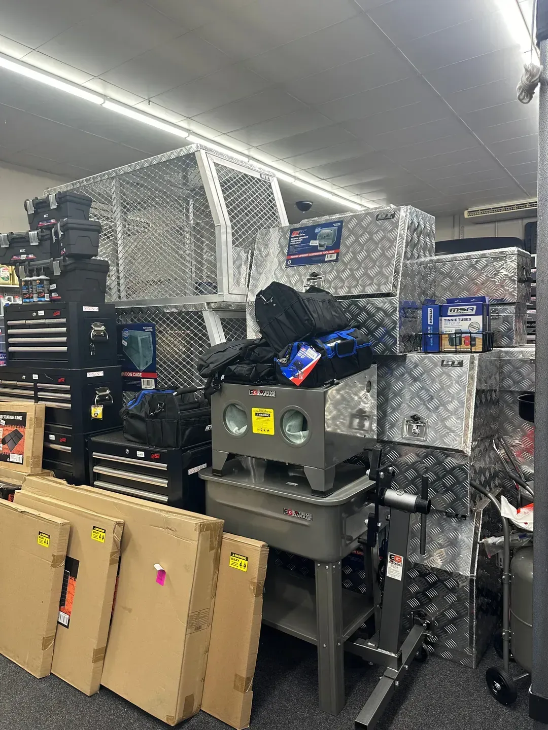 Storage Area With Stacked Equipment, Metal Shelves, and Cardboard Boxes — Autopro Taree in Wingham, NSW