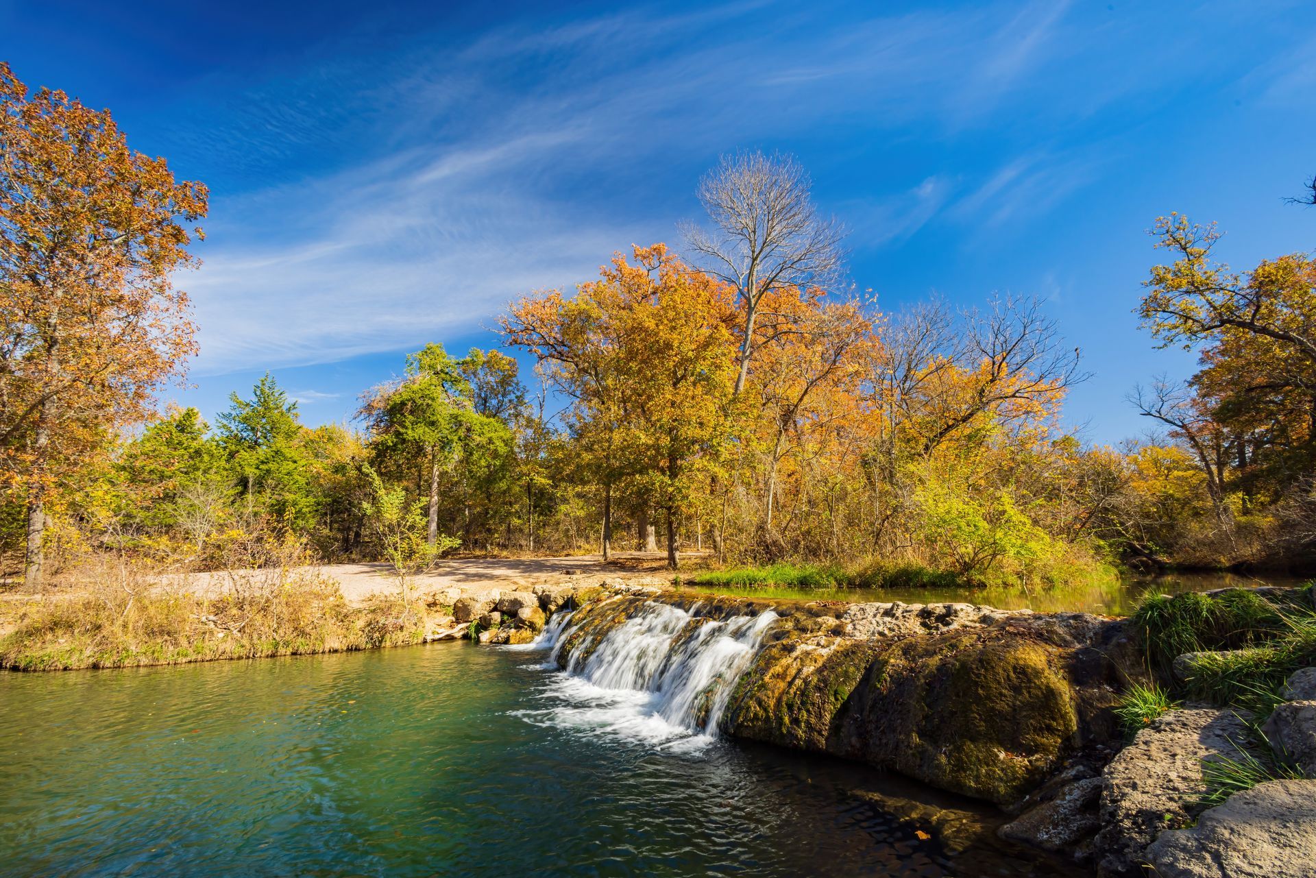 There is a waterfall in the middle of a river surrounded by trees.