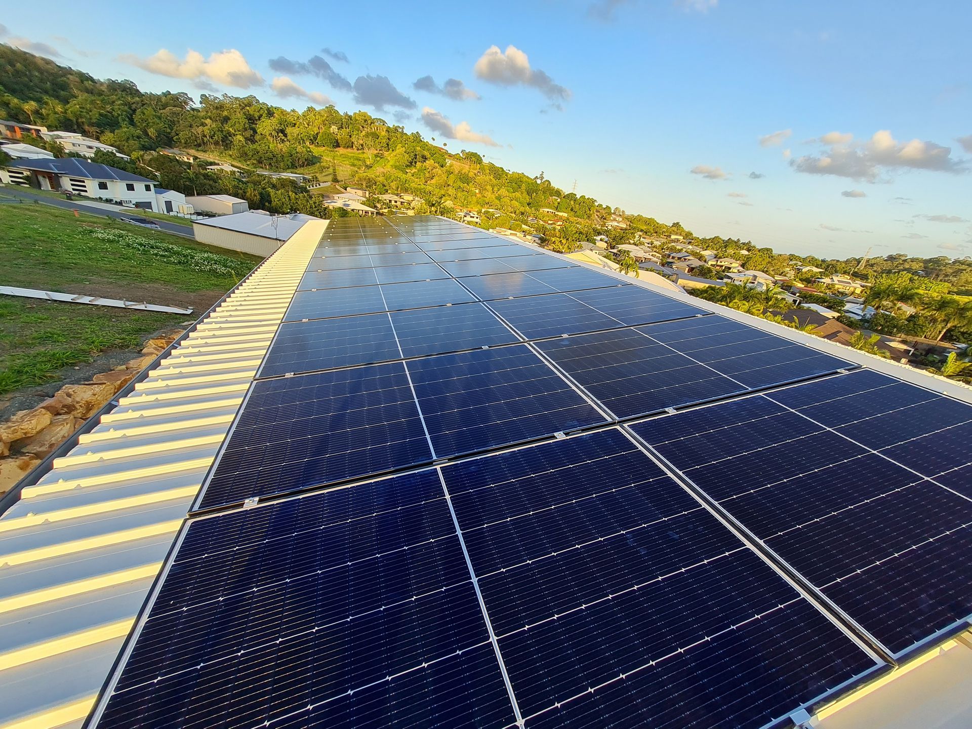 A row of solar panels are sitting on top of a white roof.