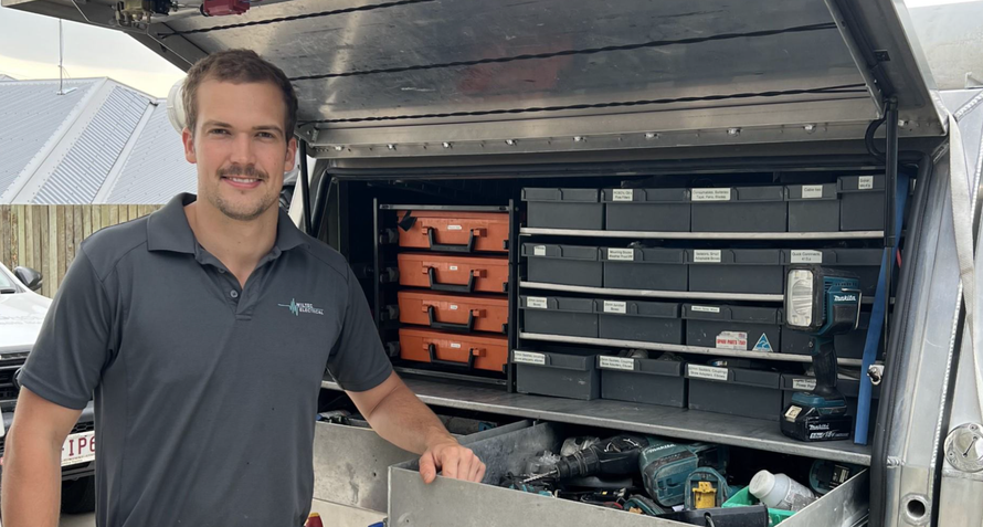 A man is standing in front of a van with the trunk open.