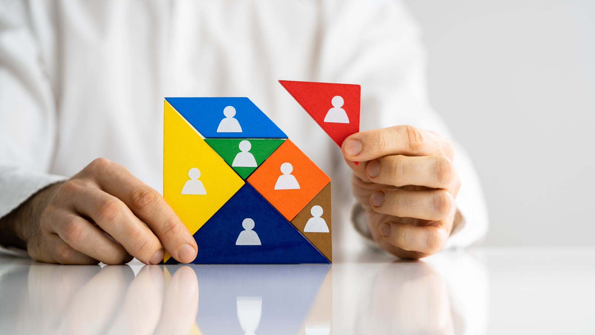 Person assembling a puzzle with people icons; concept of staffing or team building.