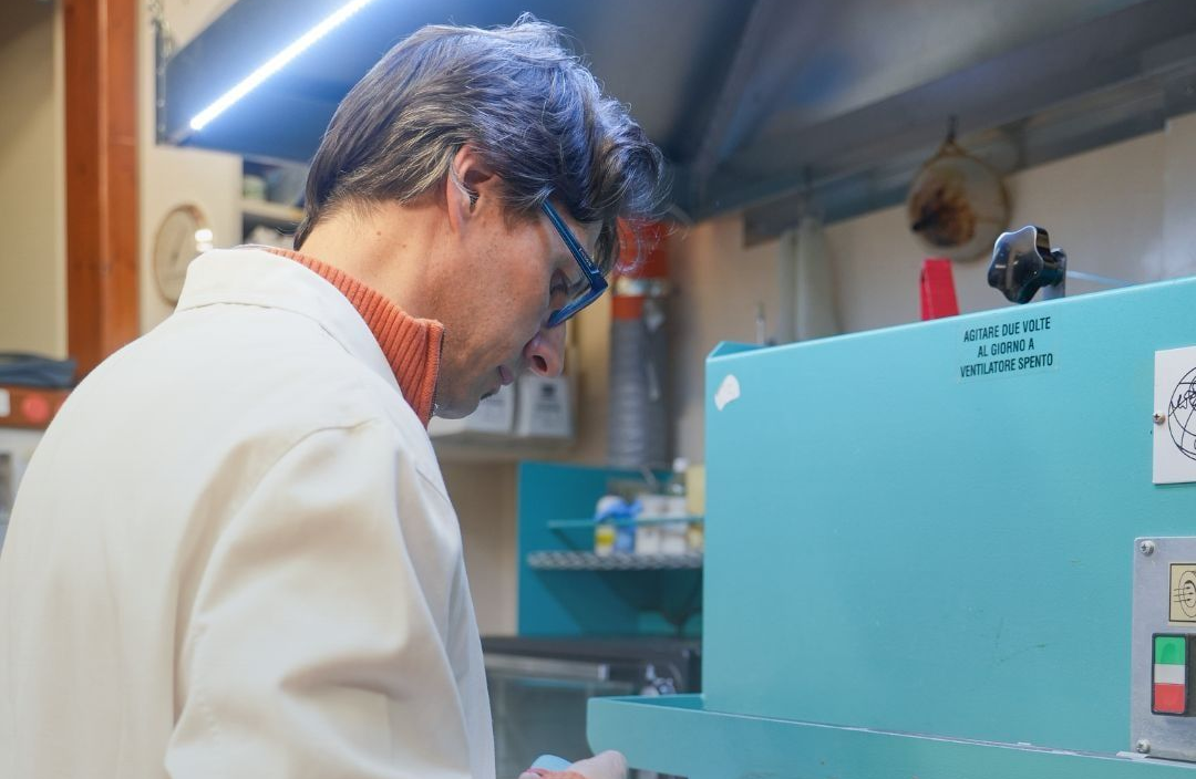 Un uomo in camice esamina le attrezzature di un laboratorio.