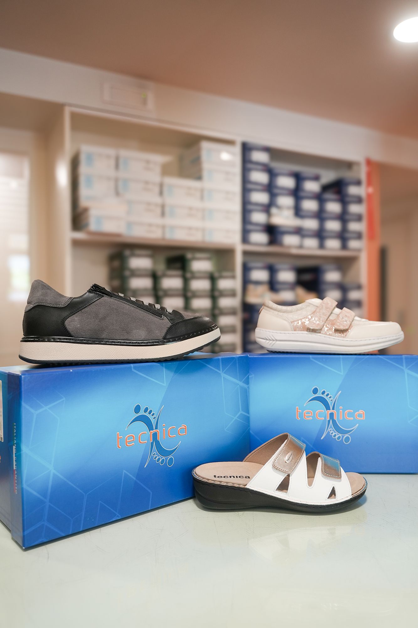 Scarpe esposte su scatole blu con lo sfondo di uno scaffale di un negozio.
